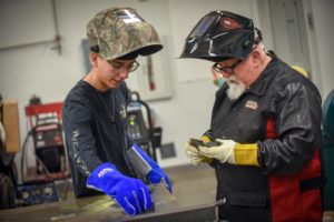 Instructor teaching student welding techniques